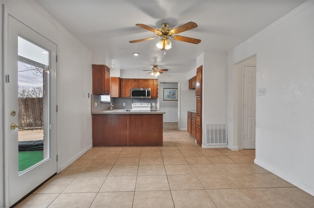 kitchen featuring light tile patterned flooring, plenty of natural light, crown molding, and kitchen peninsula