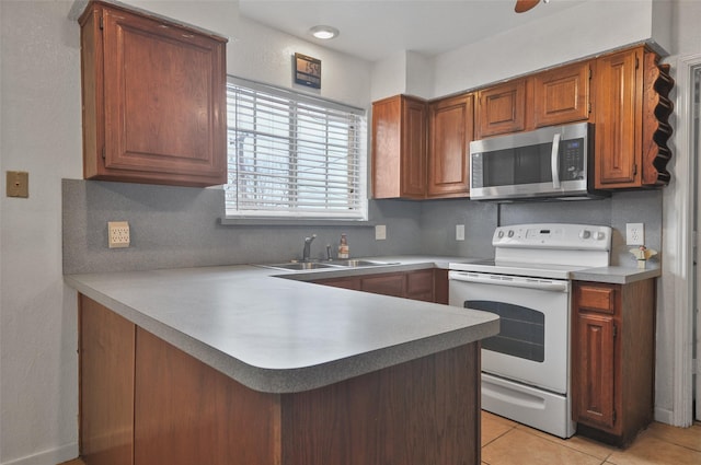 kitchen featuring white electric range oven, kitchen peninsula, sink, and light tile patterned floors