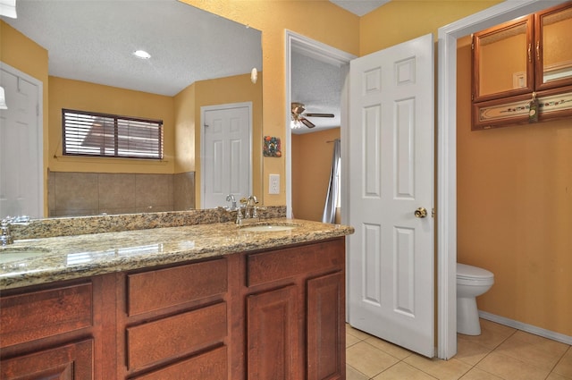 bathroom with tile patterned flooring, vanity, ceiling fan, toilet, and a textured ceiling