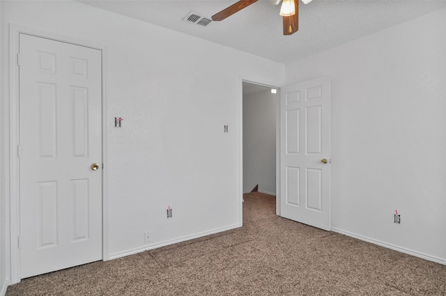 empty room featuring ceiling fan, carpet flooring, and a textured ceiling