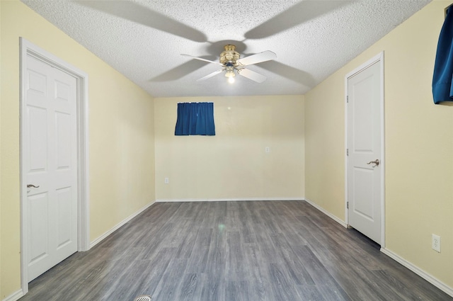 empty room with ceiling fan, dark hardwood / wood-style flooring, and a textured ceiling