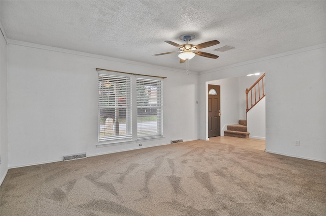 carpeted spare room featuring ceiling fan, ornamental molding, and a textured ceiling