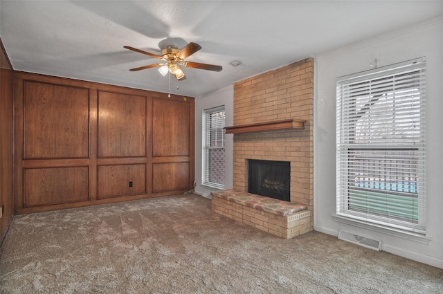 unfurnished living room featuring ceiling fan, light colored carpet, a healthy amount of sunlight, and a fireplace