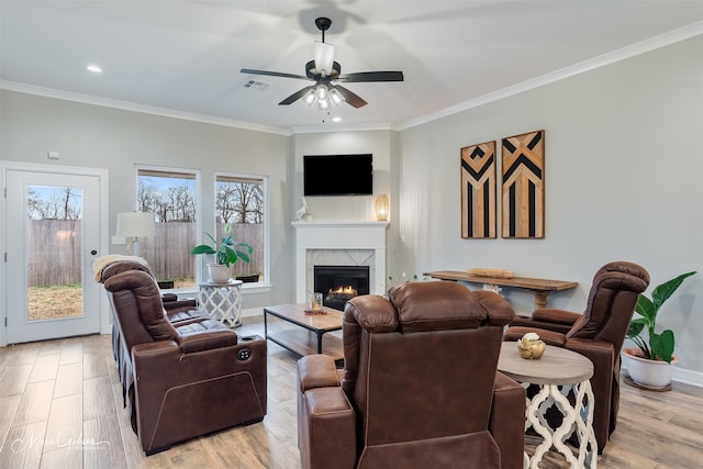 living room featuring ornamental molding, a fireplace, and light hardwood / wood-style floors