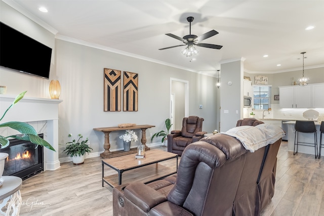 living room featuring ceiling fan, ornamental molding, and light hardwood / wood-style flooring