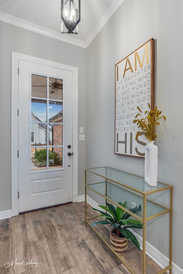 entrance foyer with ornamental molding, wood-type flooring, and a notable chandelier