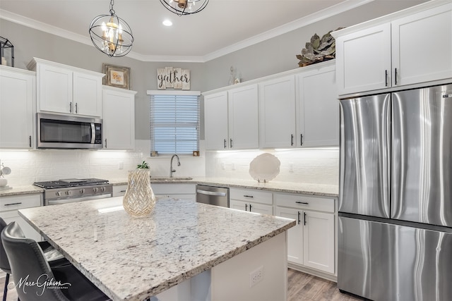 kitchen with hanging light fixtures, a kitchen island, ornamental molding, and appliances with stainless steel finishes