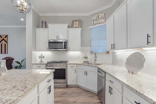 kitchen featuring stainless steel appliances, crown molding, sink, and white cabinets