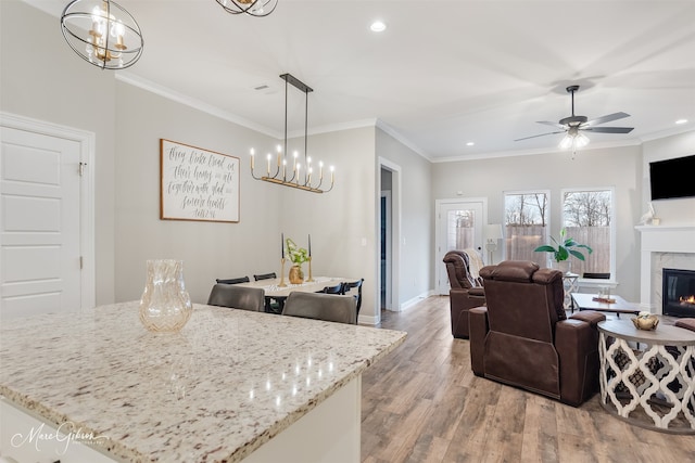 kitchen featuring light stone counters, a high end fireplace, hanging light fixtures, and light hardwood / wood-style flooring