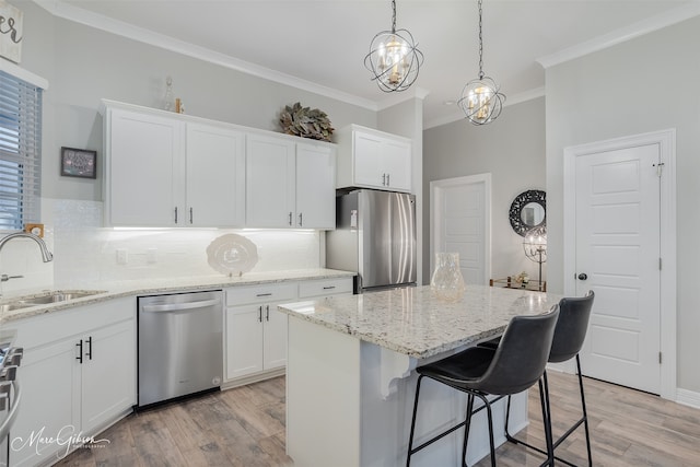 kitchen featuring pendant lighting, sink, appliances with stainless steel finishes, a center island, and white cabinets