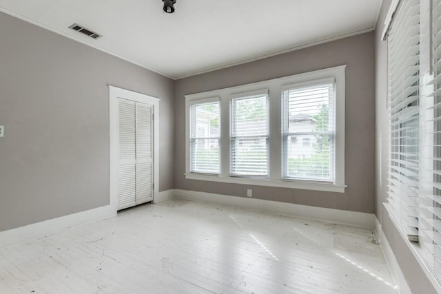 unfurnished bedroom with multiple windows, ornamental molding, and a closet