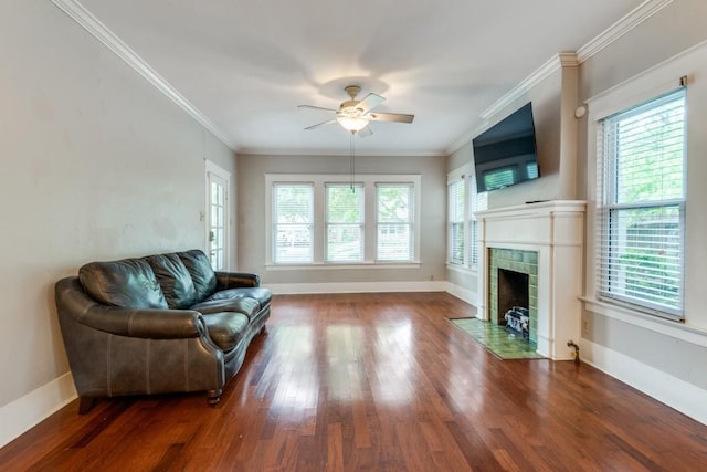 living room featuring hardwood / wood-style floors, ornamental molding, a tile fireplace, and ceiling fan