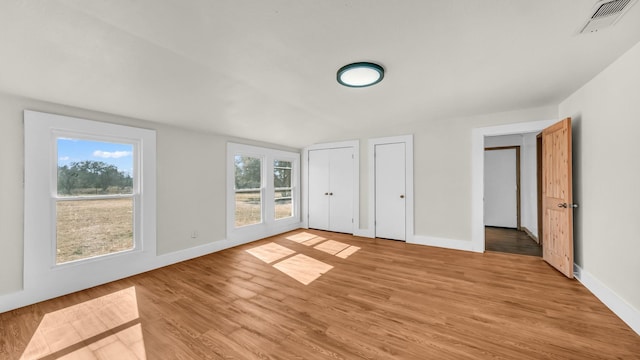 unfurnished bedroom featuring multiple closets and light wood-type flooring