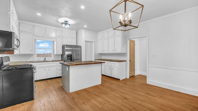 kitchen featuring sink, appliances with stainless steel finishes, butcher block counters, white cabinetry, and a center island