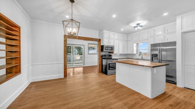 kitchen featuring a kitchen island, decorative light fixtures, butcher block counters, white cabinets, and stainless steel appliances