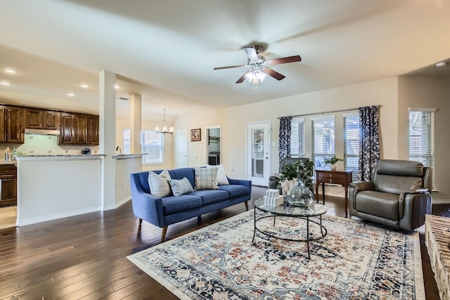 living room with ceiling fan with notable chandelier and dark wood-type flooring