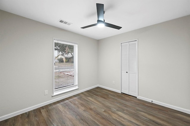 unfurnished bedroom featuring dark hardwood / wood-style floors, ceiling fan, and a closet