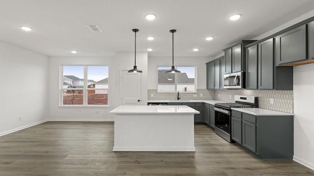 kitchen featuring pendant lighting, sink, appliances with stainless steel finishes, a center island, and decorative backsplash