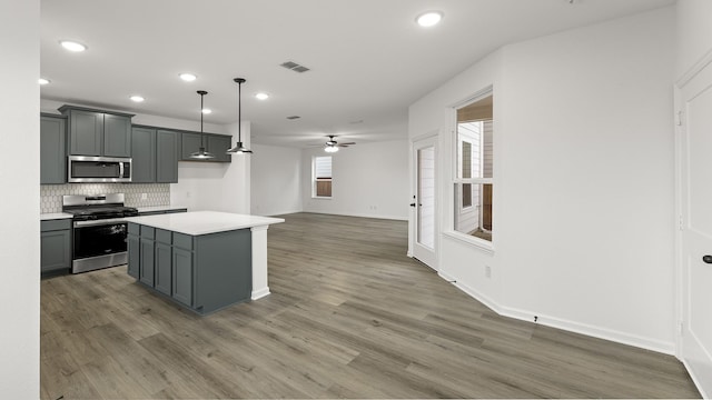 kitchen with pendant lighting, gray cabinetry, backsplash, stainless steel appliances, and a center island