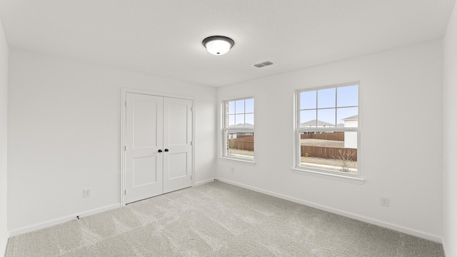 unfurnished bedroom with light colored carpet and a closet