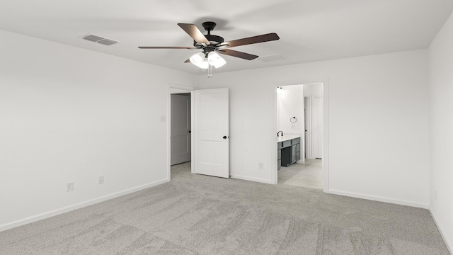 unfurnished bedroom featuring connected bathroom, light carpet, and ceiling fan