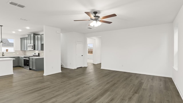 unfurnished living room featuring dark wood-type flooring, ceiling fan, and sink