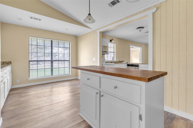 kitchen featuring butcher block countertops, dark hardwood / wood-style floors, white cabinets, a kitchen island, and decorative light fixtures