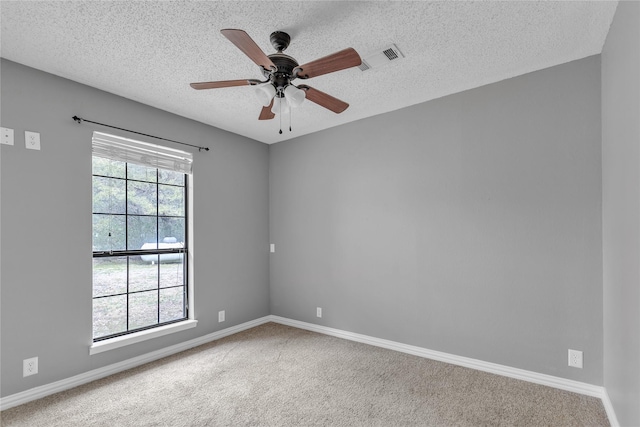 carpeted empty room with a ceiling fan, baseboards, and a textured ceiling