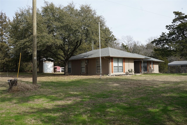 rear view of property featuring an outbuilding, a yard, and a shed