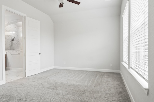 spare room with a ceiling fan, carpet flooring, vaulted ceiling, and baseboards