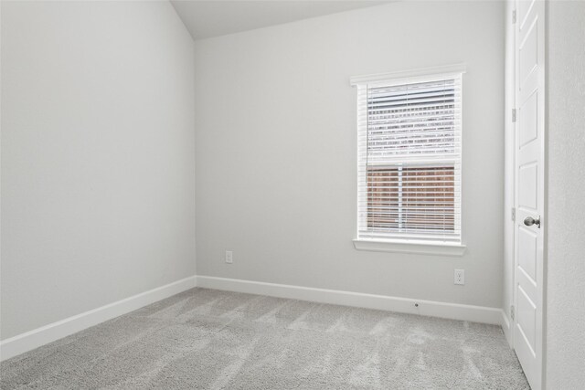 spare room featuring light carpet and baseboards