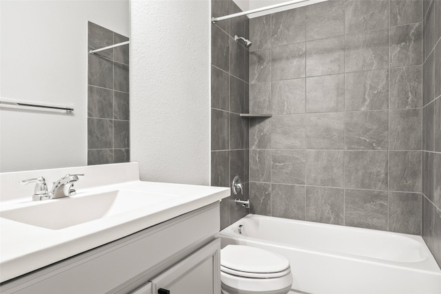 bathroom with toilet, a textured wall, washtub / shower combination, and vanity