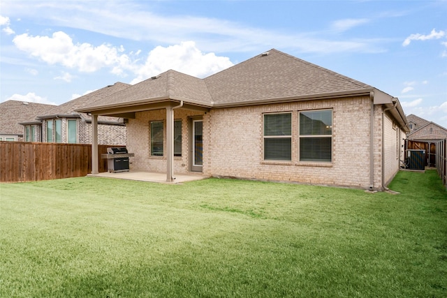 back of house featuring a patio, a fenced backyard, brick siding, a shingled roof, and a lawn