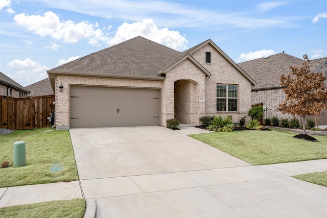 french provincial home featuring concrete driveway, brick siding, an attached garage, and a front yard