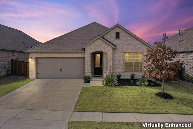 french country style house featuring brick siding, a yard, roof with shingles, concrete driveway, and a garage