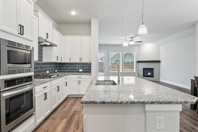 kitchen featuring open floor plan, an island with sink, a sink, and pendant lighting