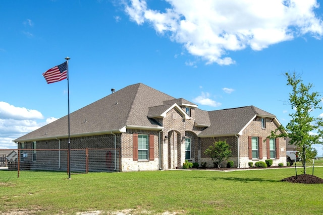 view of front of house with a shingled roof, a front yard, and brick siding