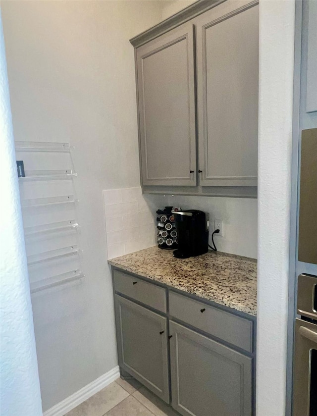 interior space featuring stainless steel oven, light stone countertops, gray cabinetry, and light tile patterned floors