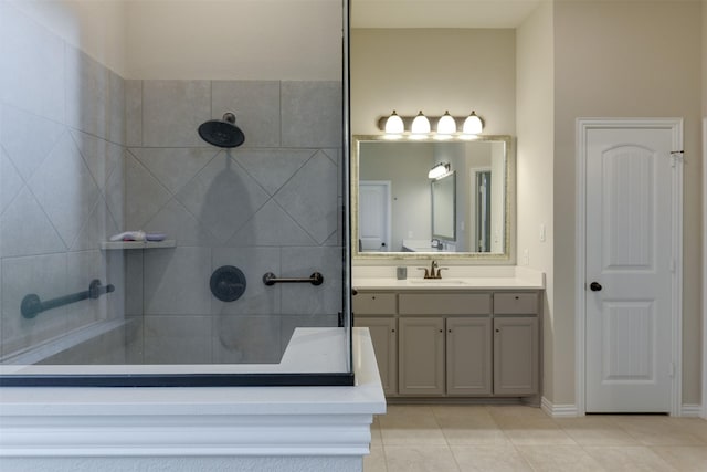 bathroom with tile patterned flooring, baseboards, a tile shower, and vanity