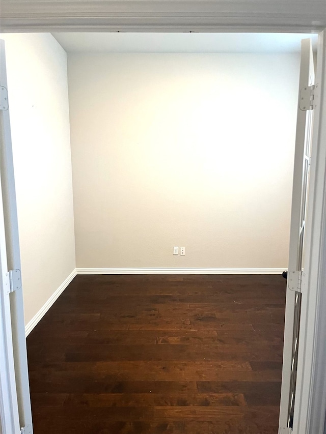 unfurnished room featuring baseboards and dark wood-style flooring