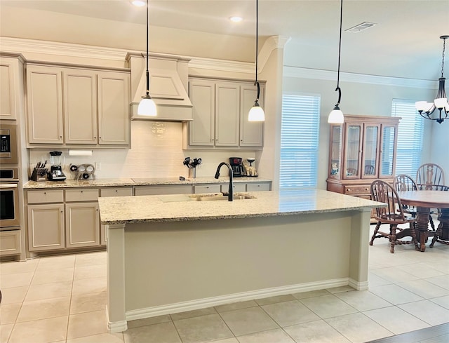 kitchen featuring sink, hanging light fixtures, a center island with sink, stainless steel appliances, and light stone countertops