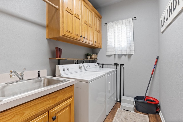 laundry room with cabinets, sink, independent washer and dryer, and light hardwood / wood-style flooring