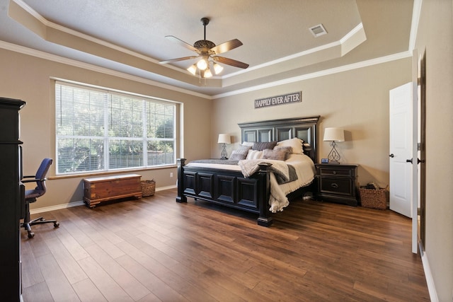 bedroom with crown molding, ceiling fan, a tray ceiling, and dark hardwood / wood-style flooring