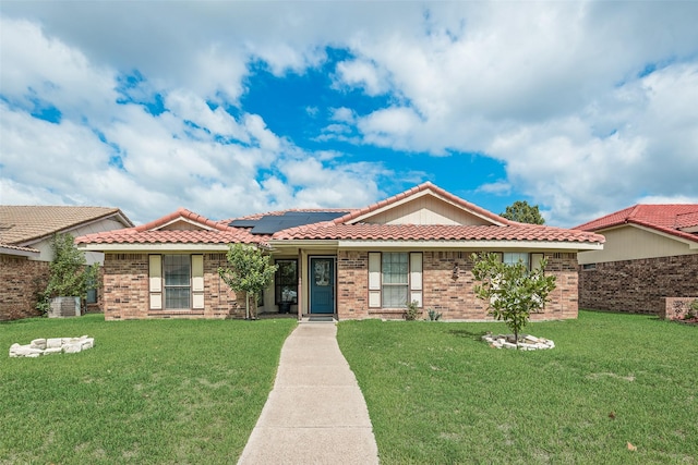 view of front of house with a front lawn and solar panels