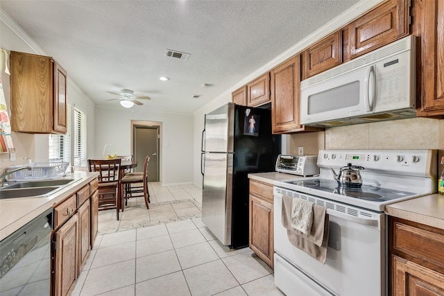 kitchen with light tile patterned flooring, sink, a textured ceiling, ornamental molding, and stainless steel appliances