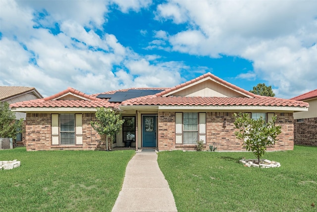 view of front of home with a front lawn and solar panels