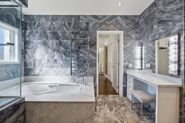 bathroom with tiled tub and tile walls