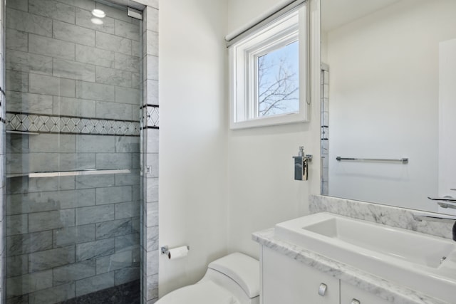 bathroom with vanity, toilet, and tiled shower