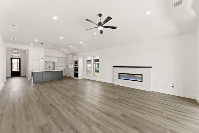 unfurnished living room featuring baseboards, visible vents, a sink, and vaulted ceiling