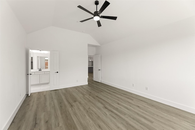 unfurnished bedroom with wood finished floors, ensuite bathroom, baseboards, and lofted ceiling
